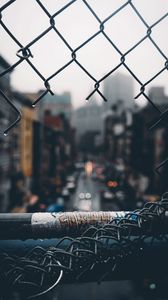 Preview wallpaper fence, grid, hole, rain, city, blur