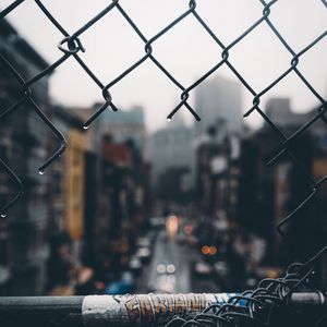 Preview wallpaper fence, grid, hole, rain, city, blur