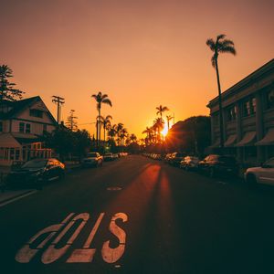 Preview wallpaper street, sunset, palm trees, road, road signs, cars